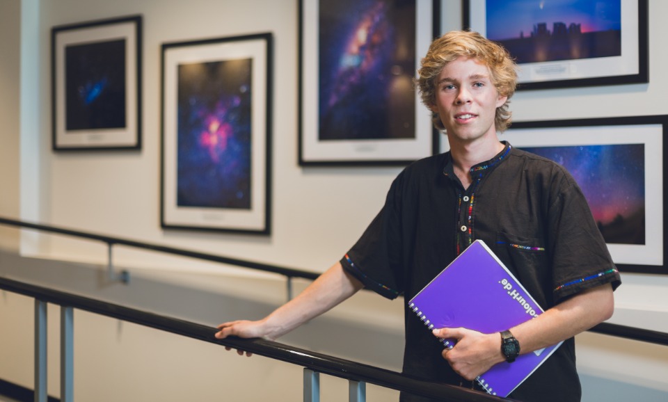 Student with notebook in front of space images