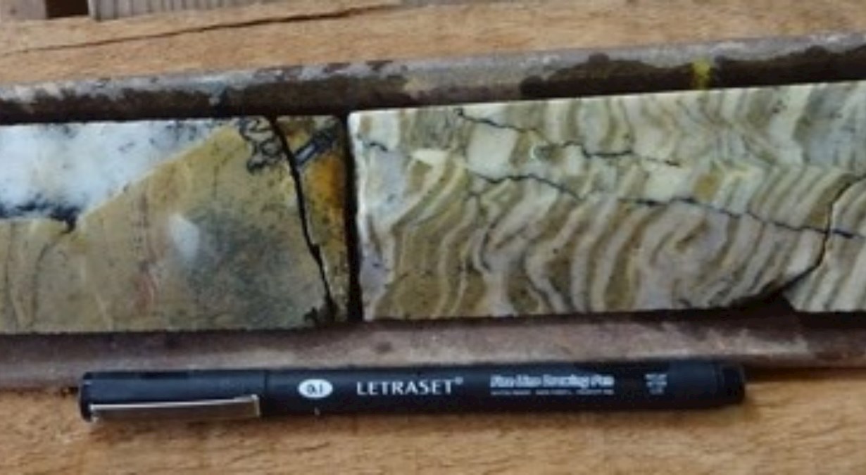 Pen laying next to a cross section of rock