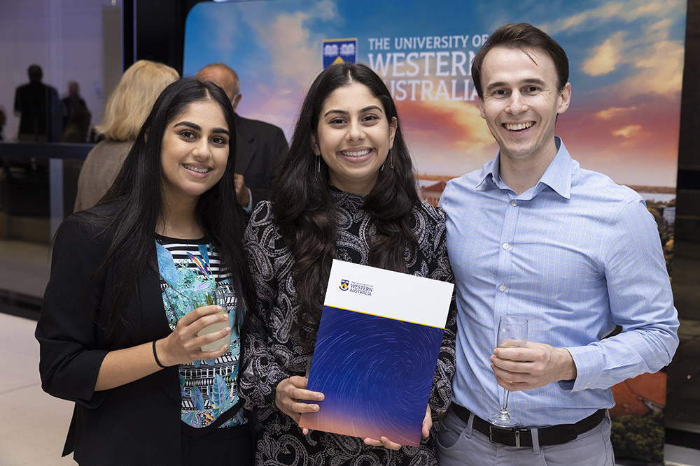 Two female and one male students in business casual attire with UWA branded award