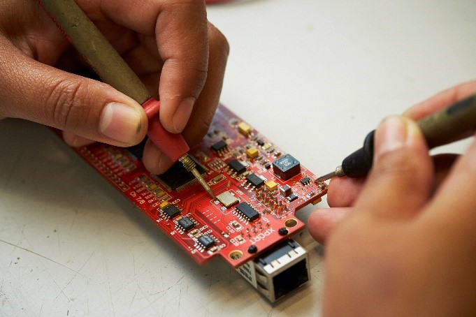 person's hands working on electronic board