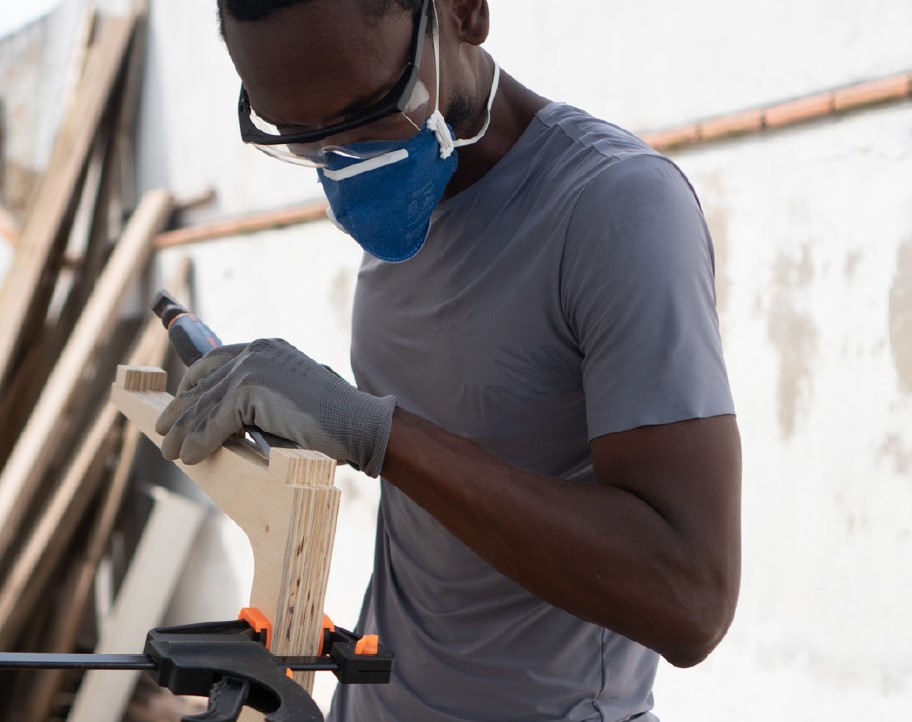 Man in t-shirt and dust mask doing woodwork