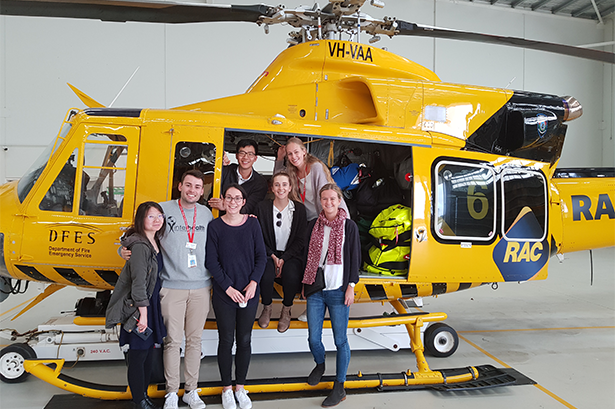 Group of students standing in front of a yellow helicopter