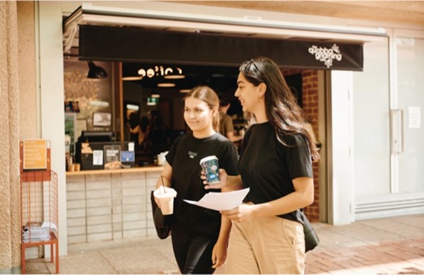 2 students walking past a cafe