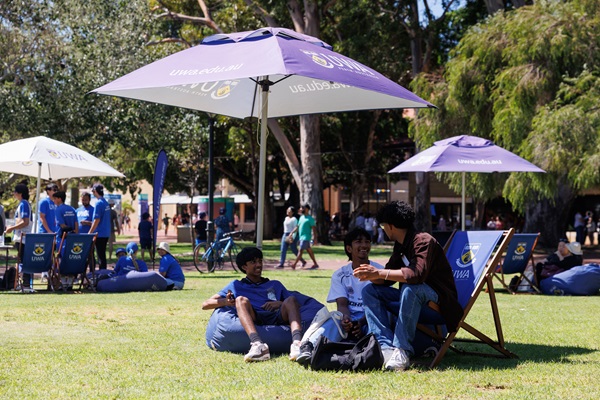 image of some student volunteers sitting on lawn chairs and bean bags under an umbrella