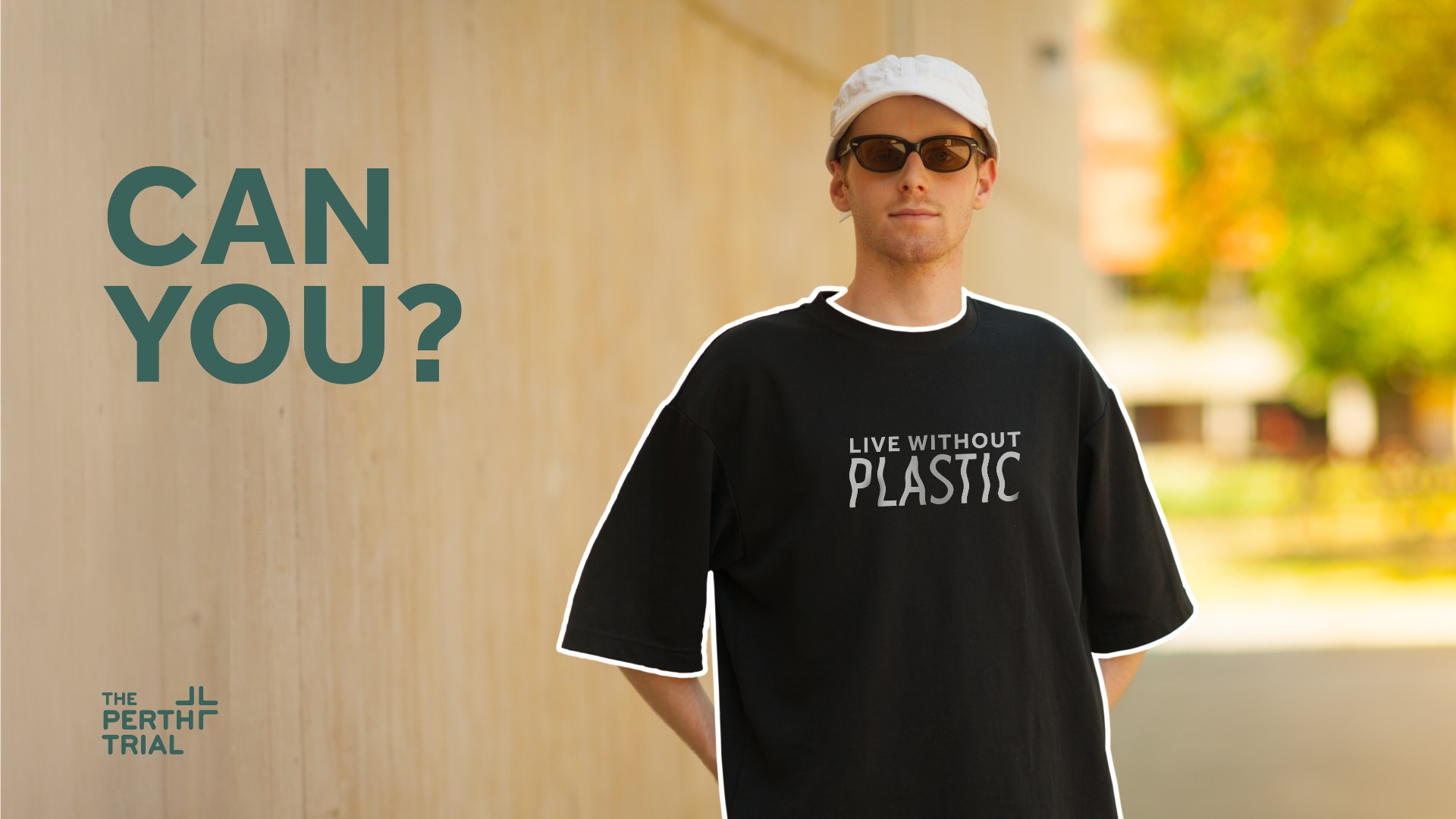 Man standing in front of wall wearing a black t-shirt that says 'live without plastic'