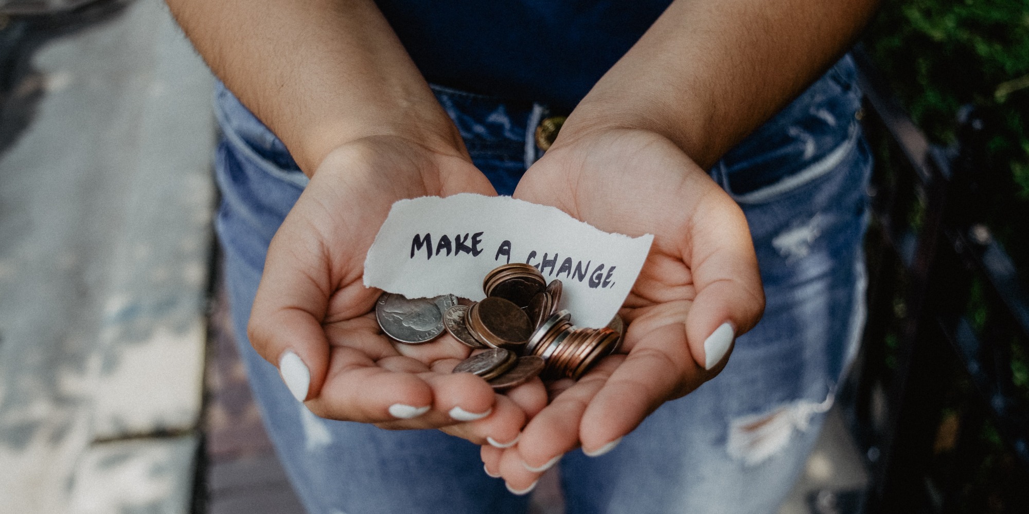 Person showing both hands with ‘make a change’ note and coins