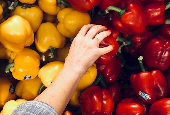 person reaching for red and yellow capsicum
