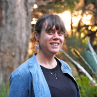 A woman standing in the UWA sunken gardens at Golden hour