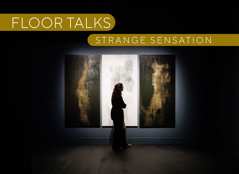 A young woman contemplates a large artwork made of three panels that hangs in a dark gallery space