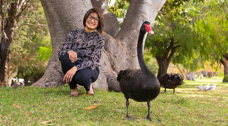 Associate Professor Parwinder Kaur next to black swan