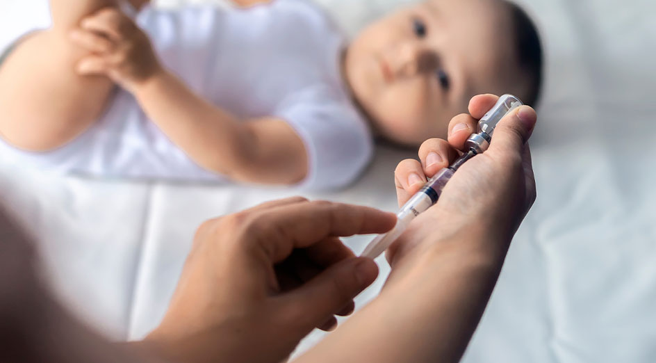 hand holding needle  with out of focus baby in background