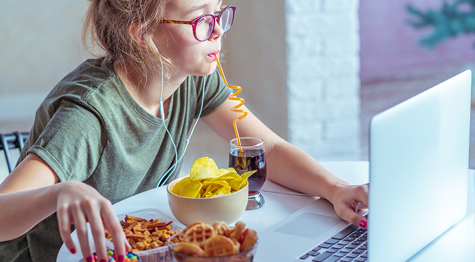 Children eating junk food while working on laptop