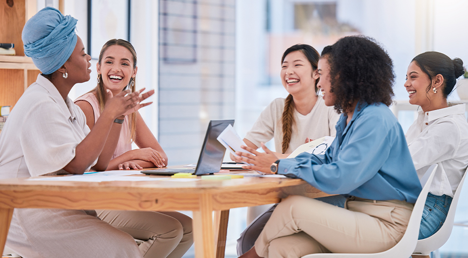 Smiling women sitting around a desk at work