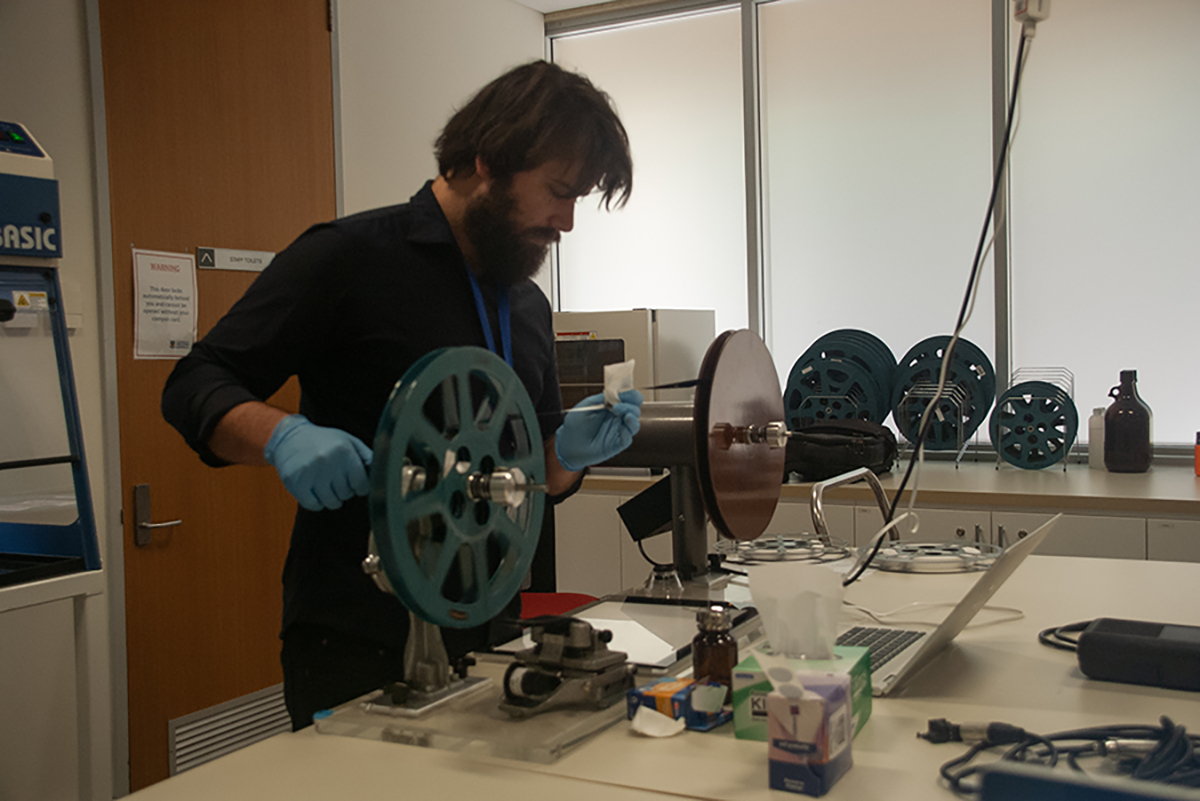 A digitisation officer widning through and cleaning a film. Image pixel length is 1200