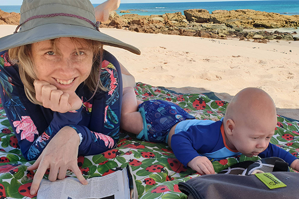 Woman lying on the beach with her baby
