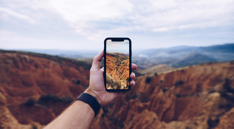 Hand holding mobile phone in front of nature