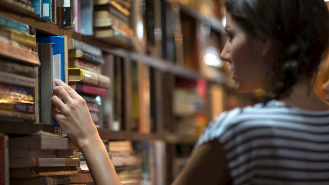 Young woman selecting a book from a shelf