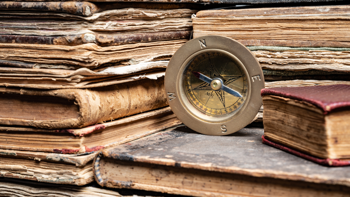 compass on stack of antique hard cover books
