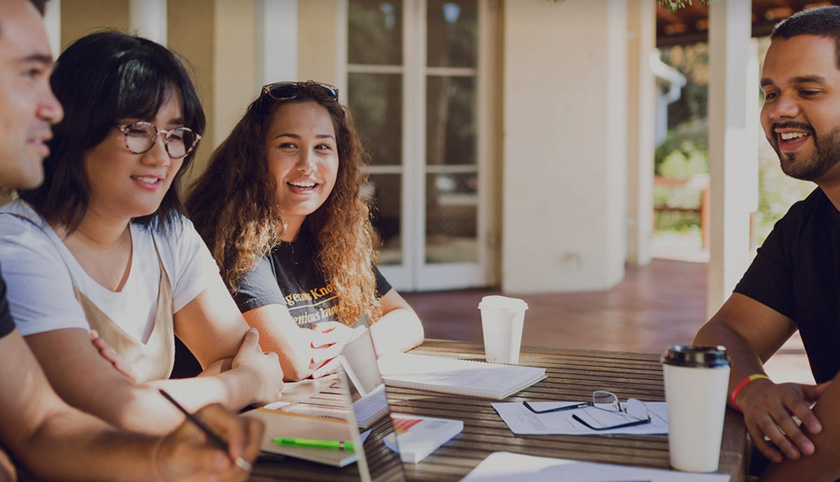 Students around a table conversing