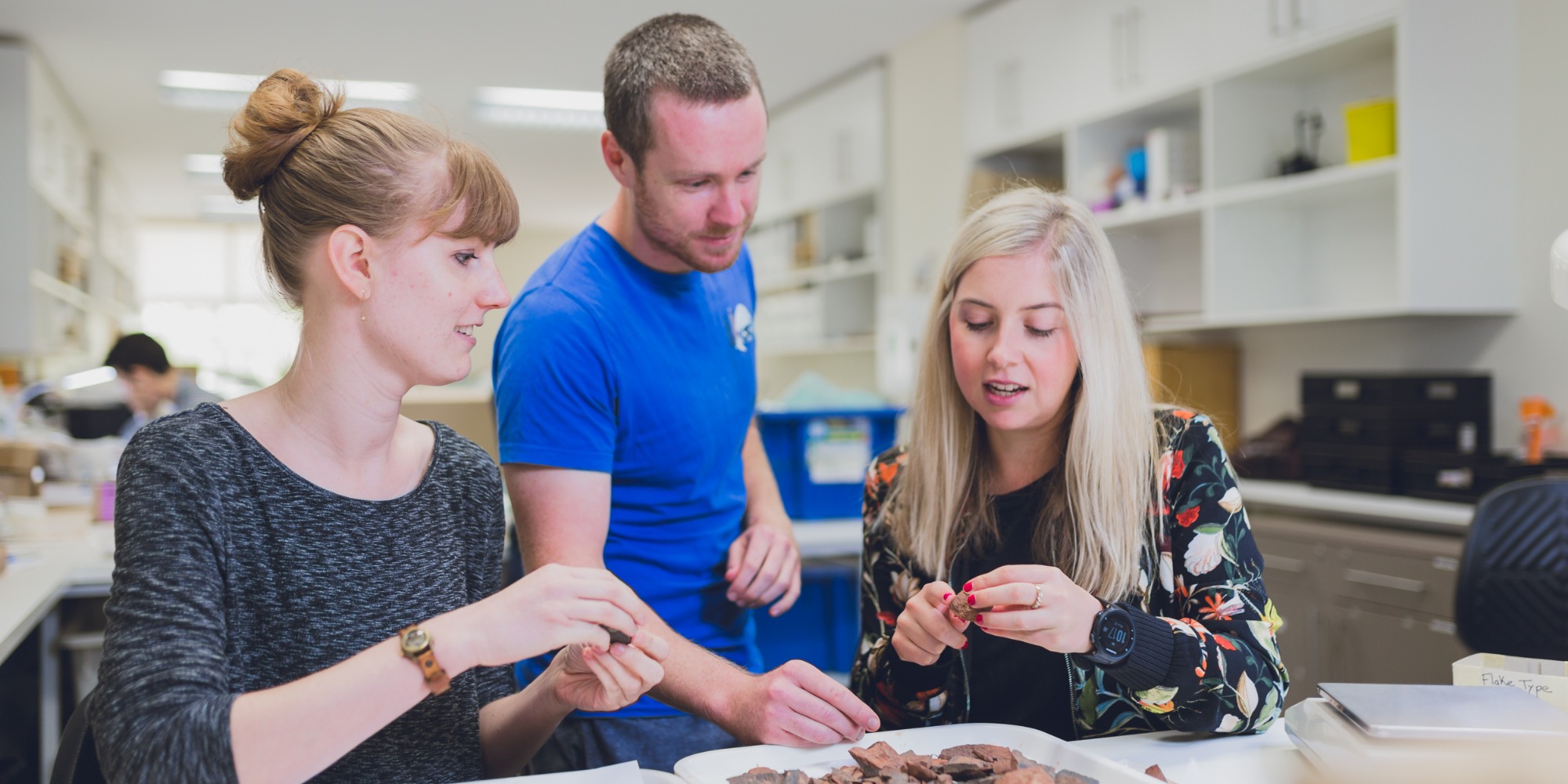 Three students look at rocks