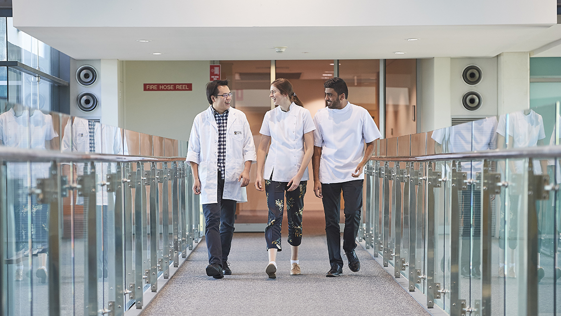 3 students walking down a hallway