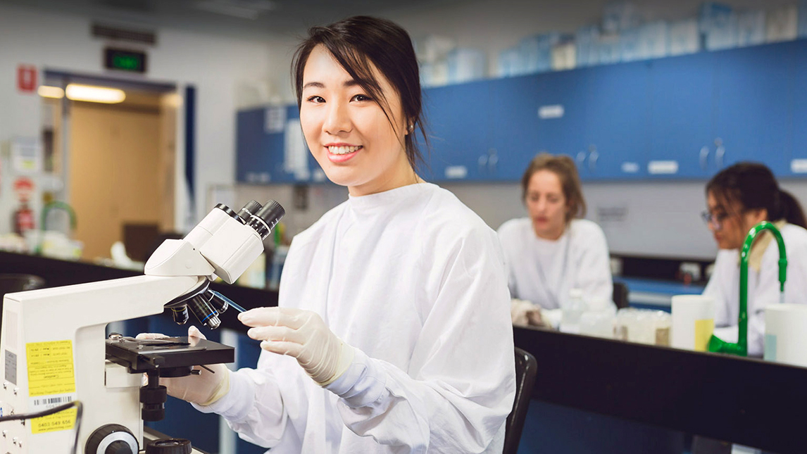 Woman in doctors coat  in lab at microscope