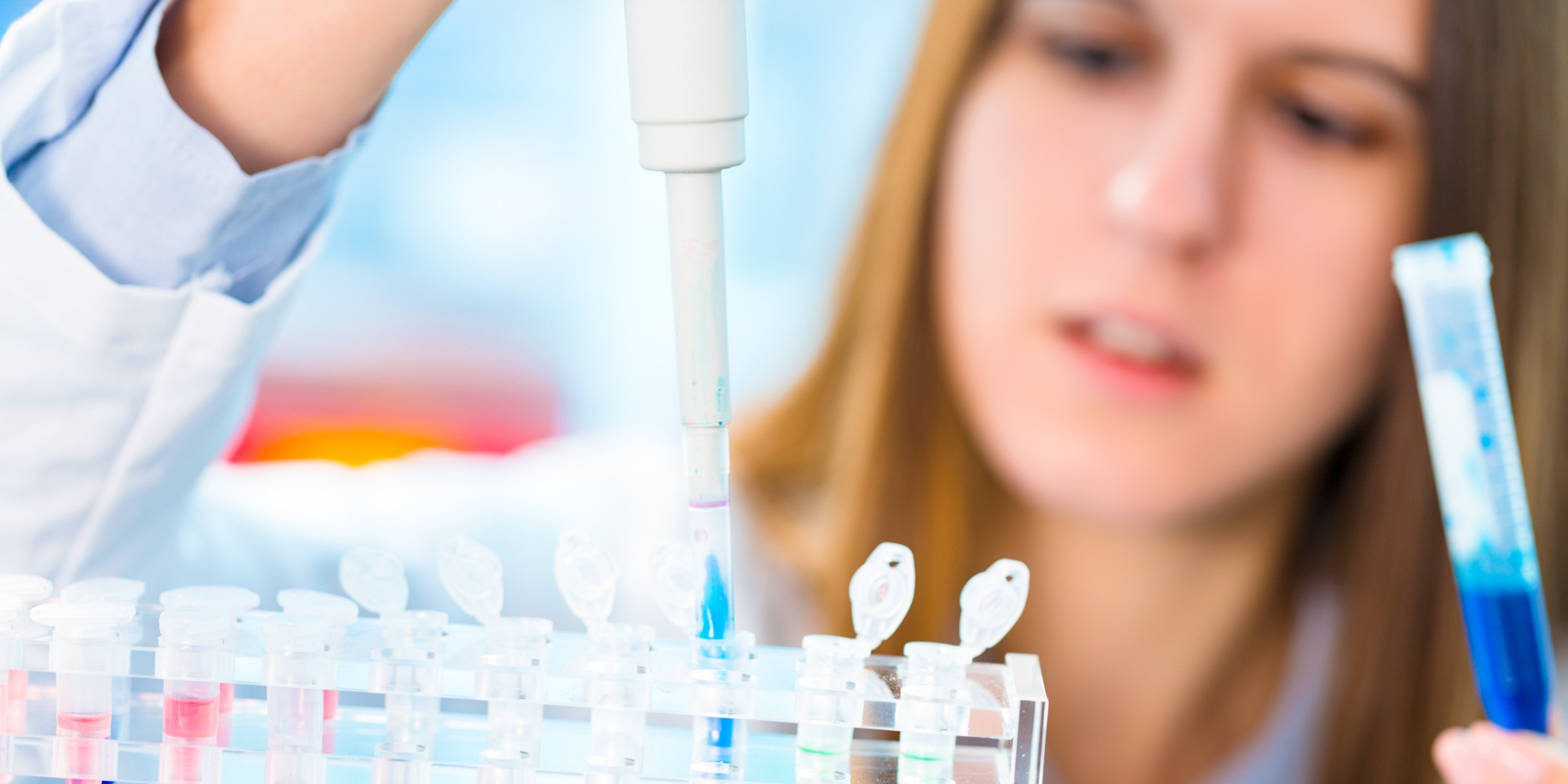 scientist drops blue liquid in vials