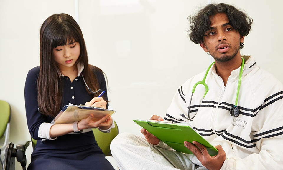 two medical students with clipboards listening to feedback