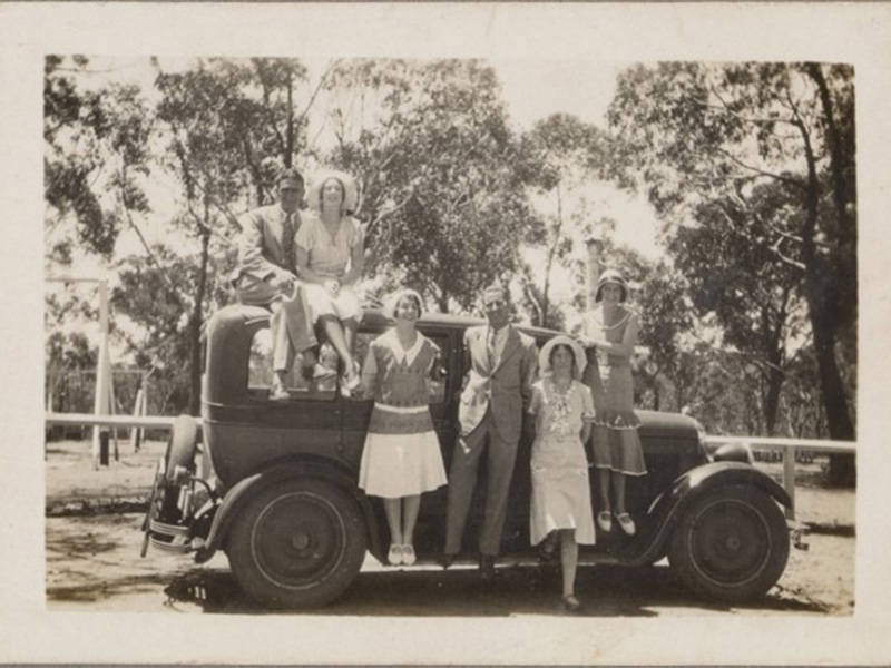 A page out of the White family album with a single photo of 3 people standing on a truck, in the early  to mid 20th century