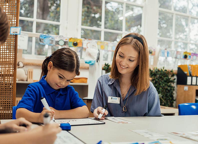 Teacher working with primary school student at their desk