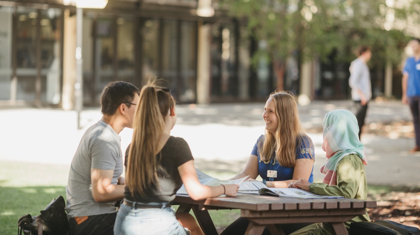Students sitting at a table outside with a UWA staff member