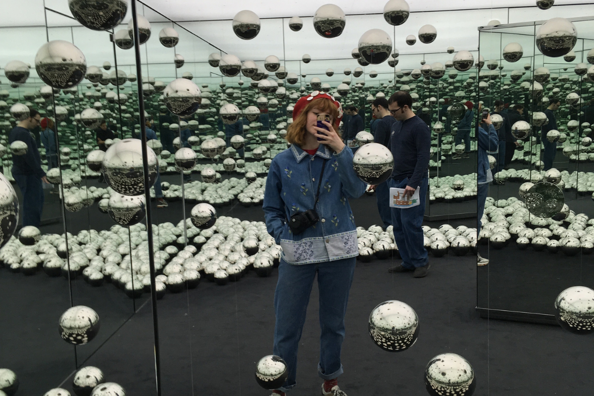 UWA Fine Arts student Zoe taking a selfie at a gallery, surrounded by silver balls and mirrors