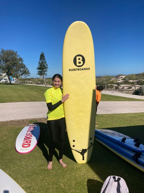 Chandini holding a surf board at the beach