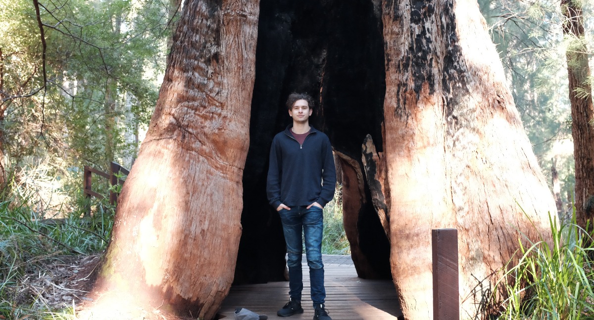 Elliott in front of large tree trunk