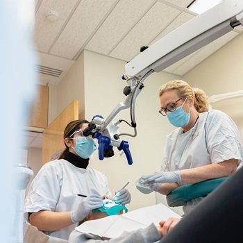 Two dentists working in a clinic with a patient in the dentist chair