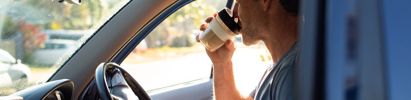 man in car drinking coffee