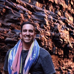 Man standing outdoors in front of rock face