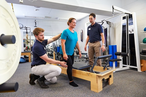 Male physios work with a female client