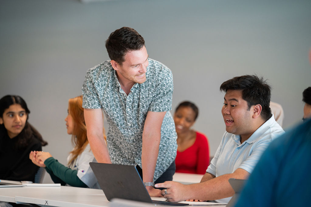 a teacher helping a student on a laptop