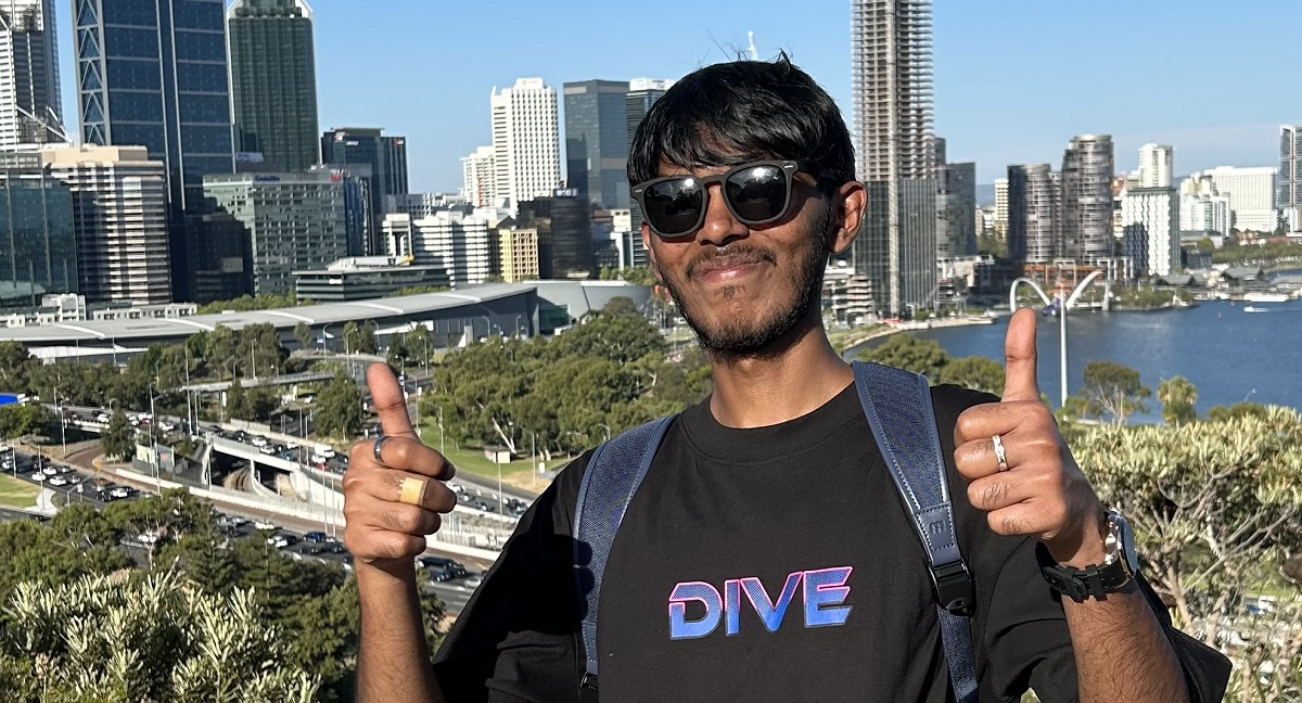 Junaid standing in front city skyline with thumbs up 