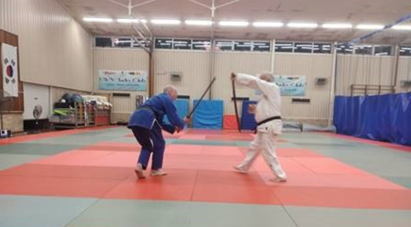 Two men, one dressed in white and one in blue, practice Aikido.