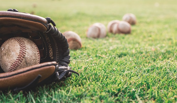 A baseball mitt and a number of baseballs on grass