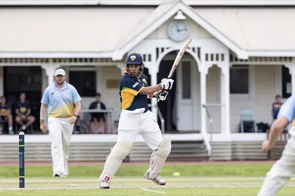 A UWA Cricket Club player bats the ball in front of the Irwin Street Building at James Oval