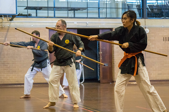 Members of the Kobudo Club training while holding wooden staffs