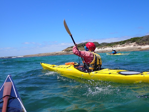 A UWA Outdoor Club member paddling in a yellow kayak.
