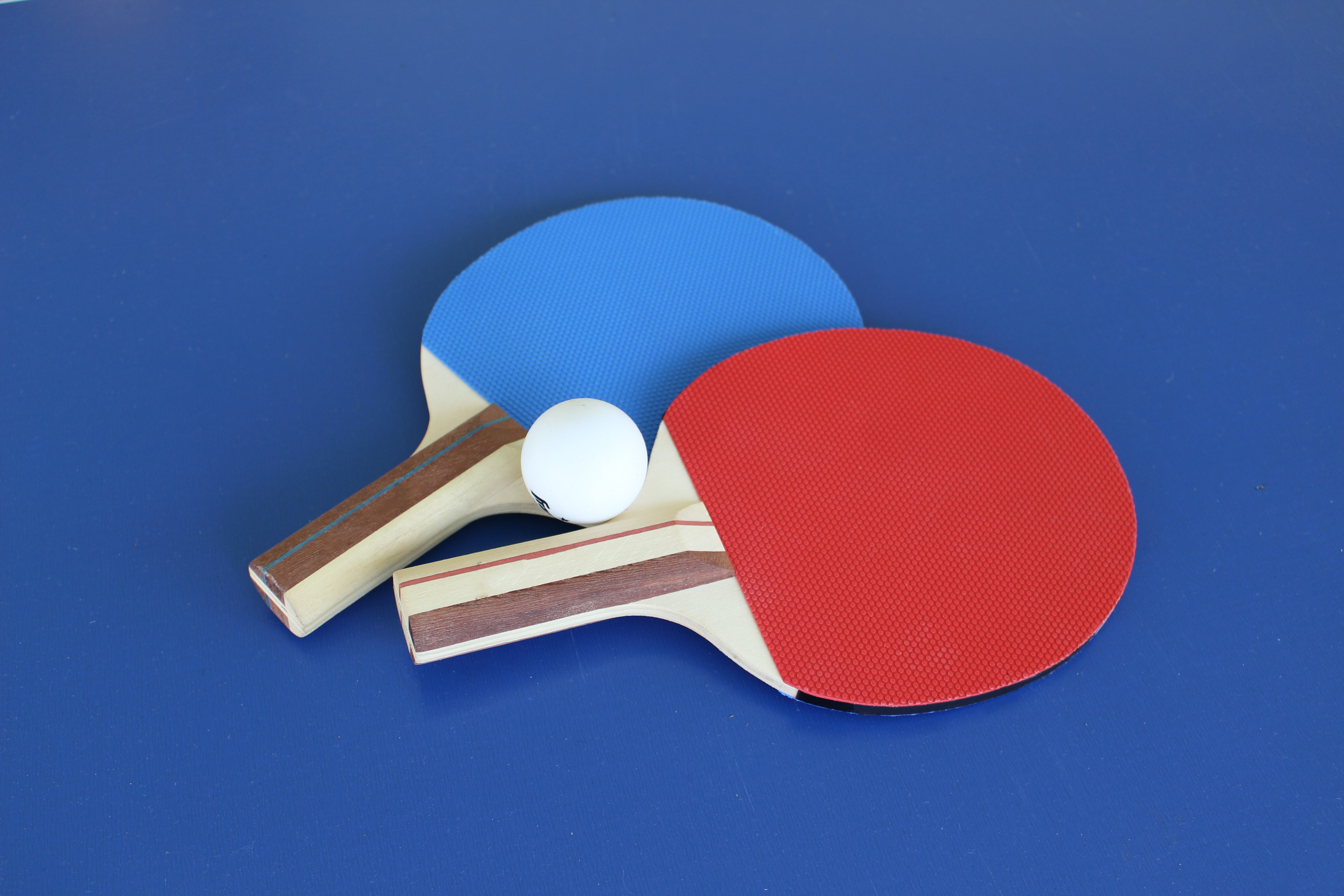Two table tennis paddles on a blue surface