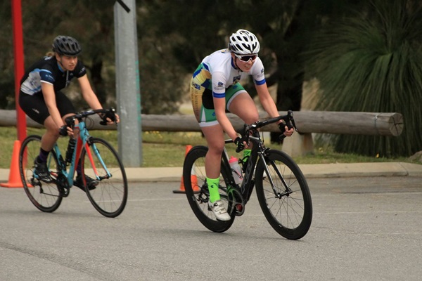 A UWA Triathlon Club member is riding a bike ahead of a member of a competing club