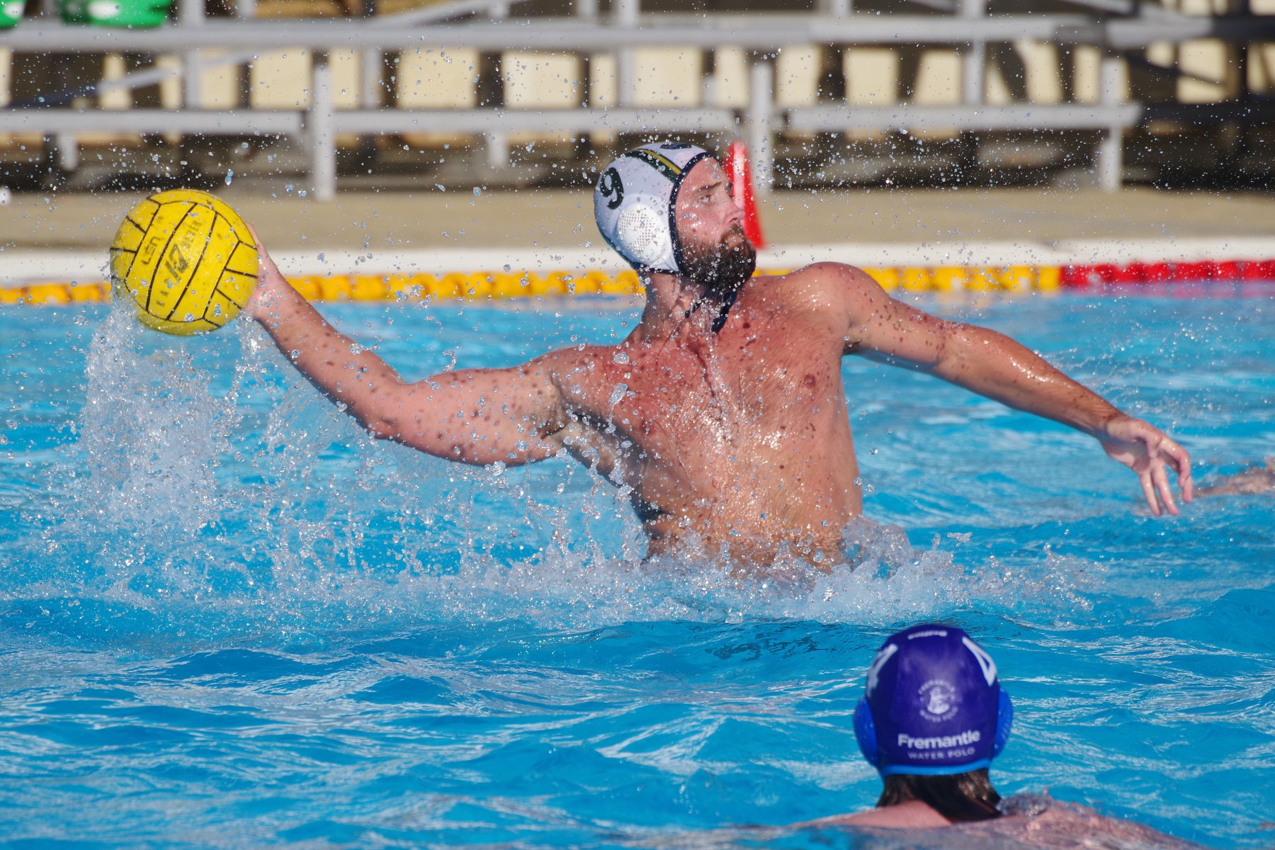 A UWA Water Polo Club member is preparing to throw a yellow water polo ball