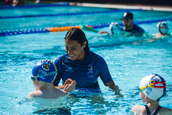 An instructor smiles and gives their student a high five while in the water.