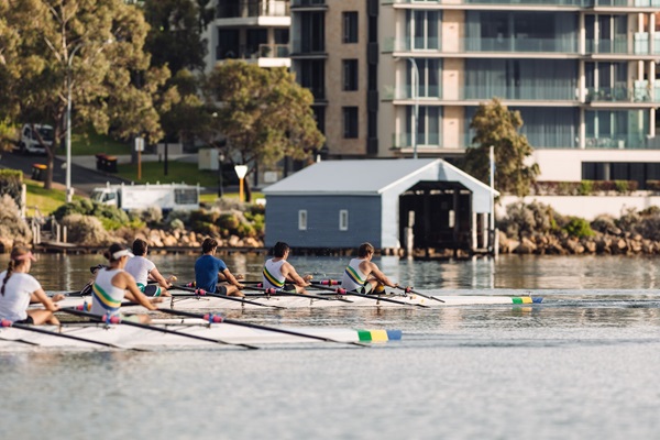 Members of the UWA boat club row past the Crawley Edge blue boat shed on the Swan River